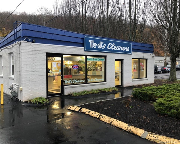 Ted's Cleaners building with a blue roof and sign, on a cloudy day.
