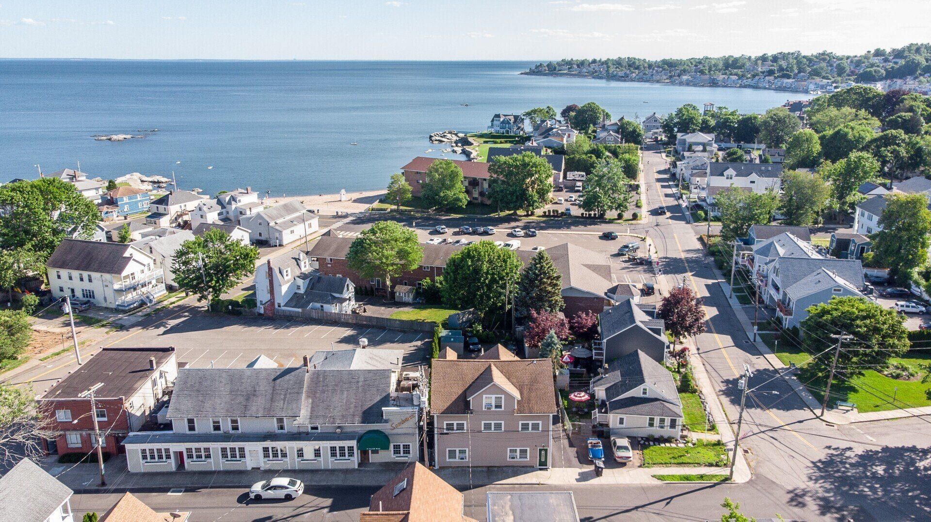 Aerial view of coastal town with houses, a road, beach, and ocean.