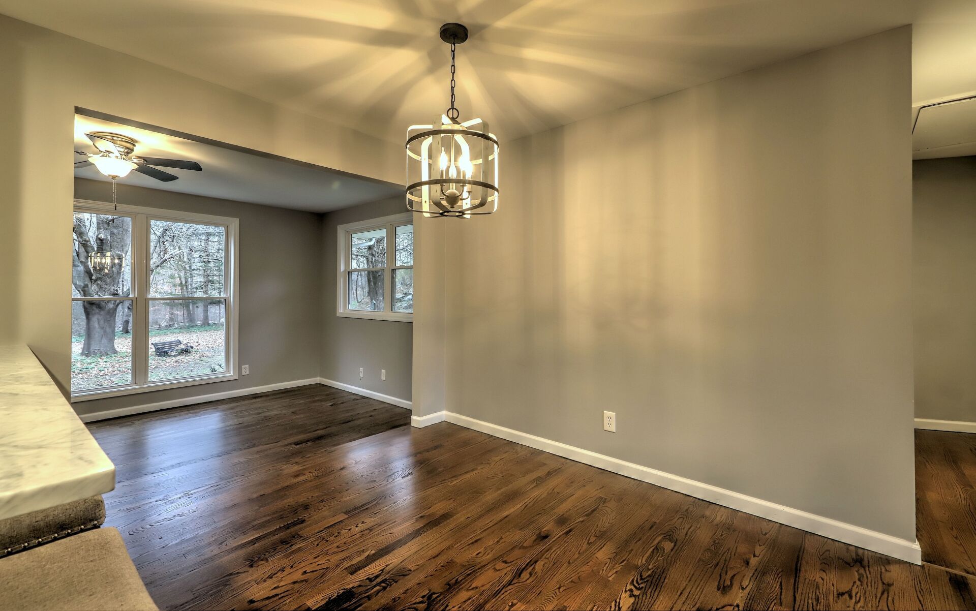 Dining room with hardwood floors, gray walls, and chandelier.