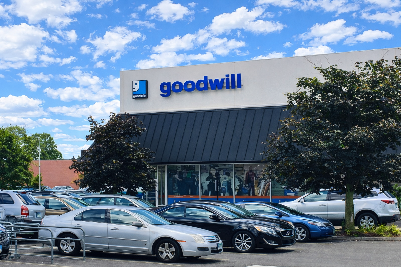 Shopping center exterior with cars in the parking lot. Stores include Ocean State Job Lot and Goodwill on a sunny day.