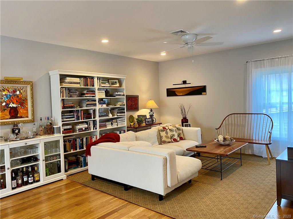 Living room with white sofa, bookshelves, art, and natural light.