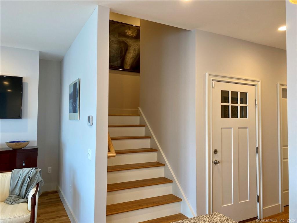 Interior view: staircase leading upward, doorway with white door, art on wall.