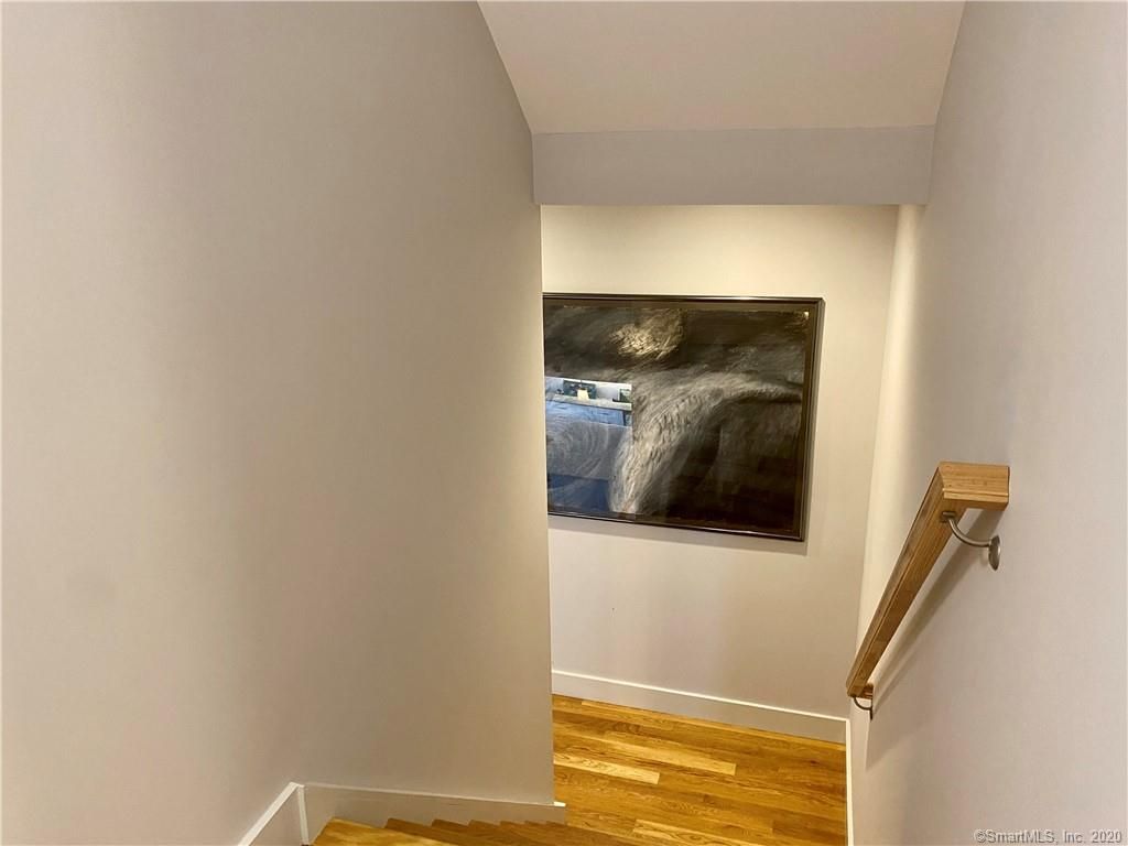 View down a hallway with a painting on the wall, wooden floor and a wooden handrail.