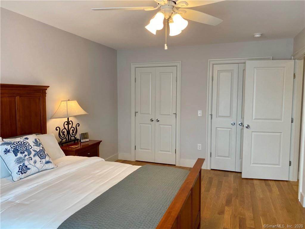 Bedroom with a wooden bed, nightstand, and two white closet doors. Ceiling fan.
