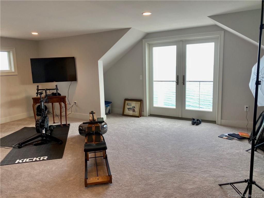 A home gym with a rowing machine and TV. The room has a window with a view of the water.