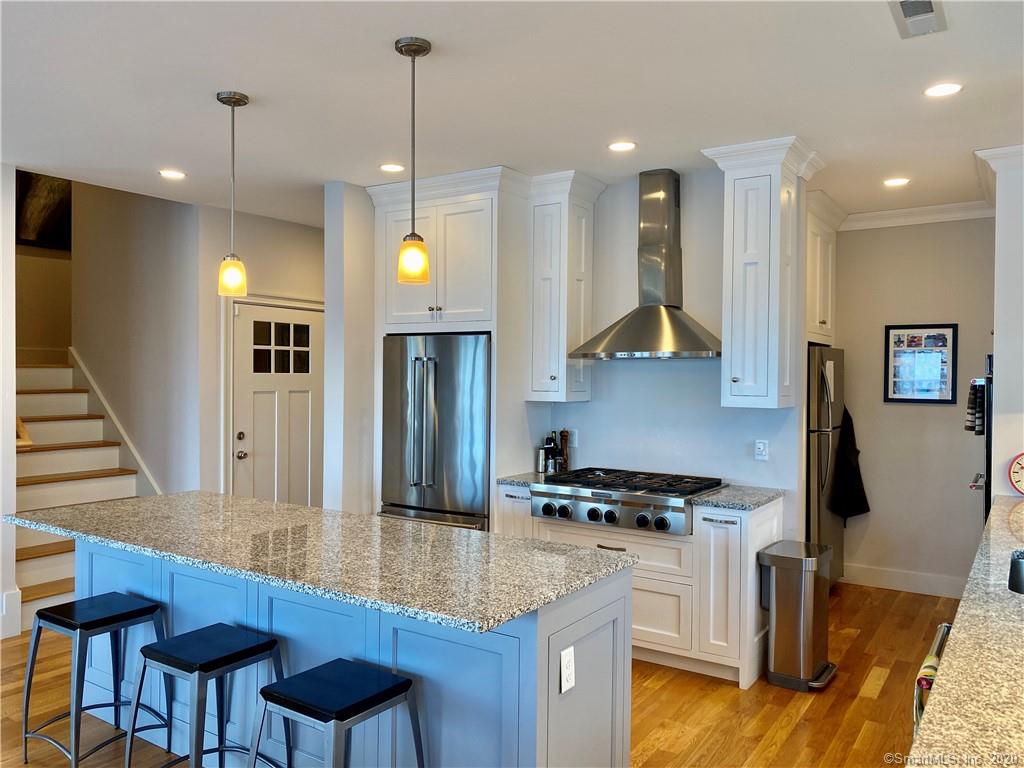 A modern kitchen with a large island, stainless steel appliances, and white cabinets.