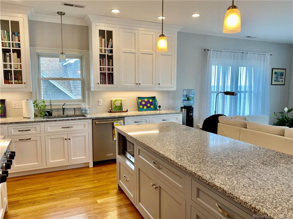 Bright kitchen with white cabinets, granite countertops, island, and wood floors.