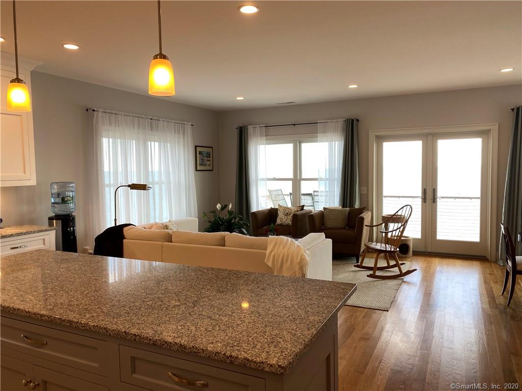 Open concept living space: kitchen island, living room with sofa, rocking chair, and glass doors.