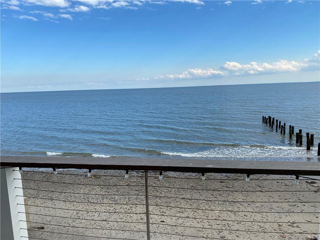 Blue water under a clear sky. A wooden structure juts out into the water.