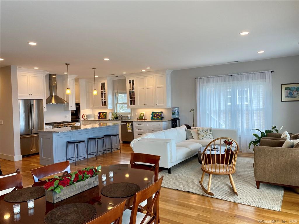Open-concept kitchen and living area with a large island, white cabinets, and a white sofa.