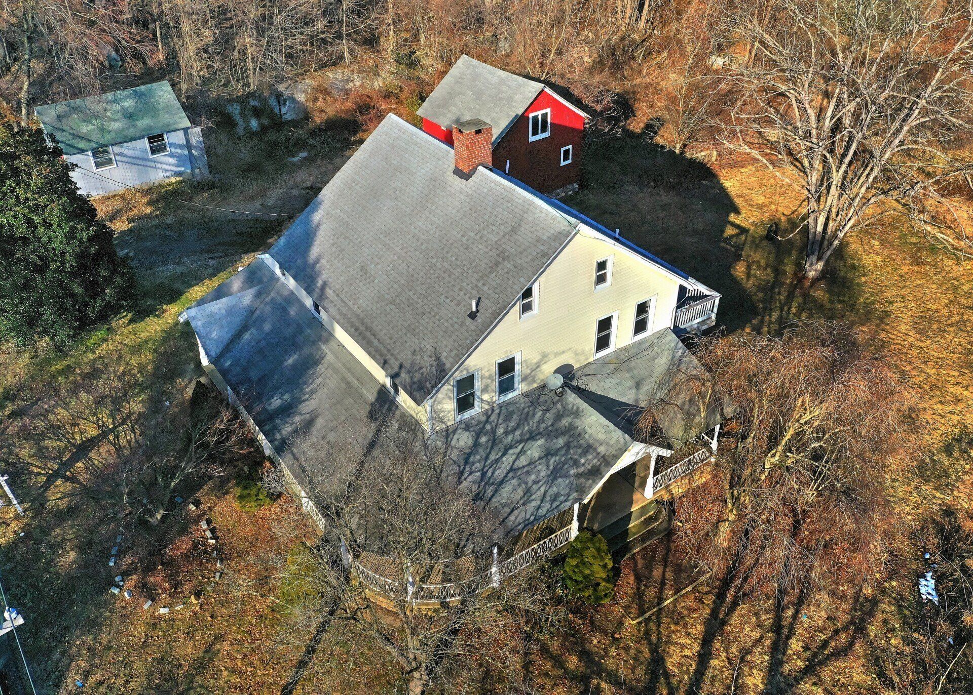 Aerial view of a two-story beige house with a dark roof and a red addition.
