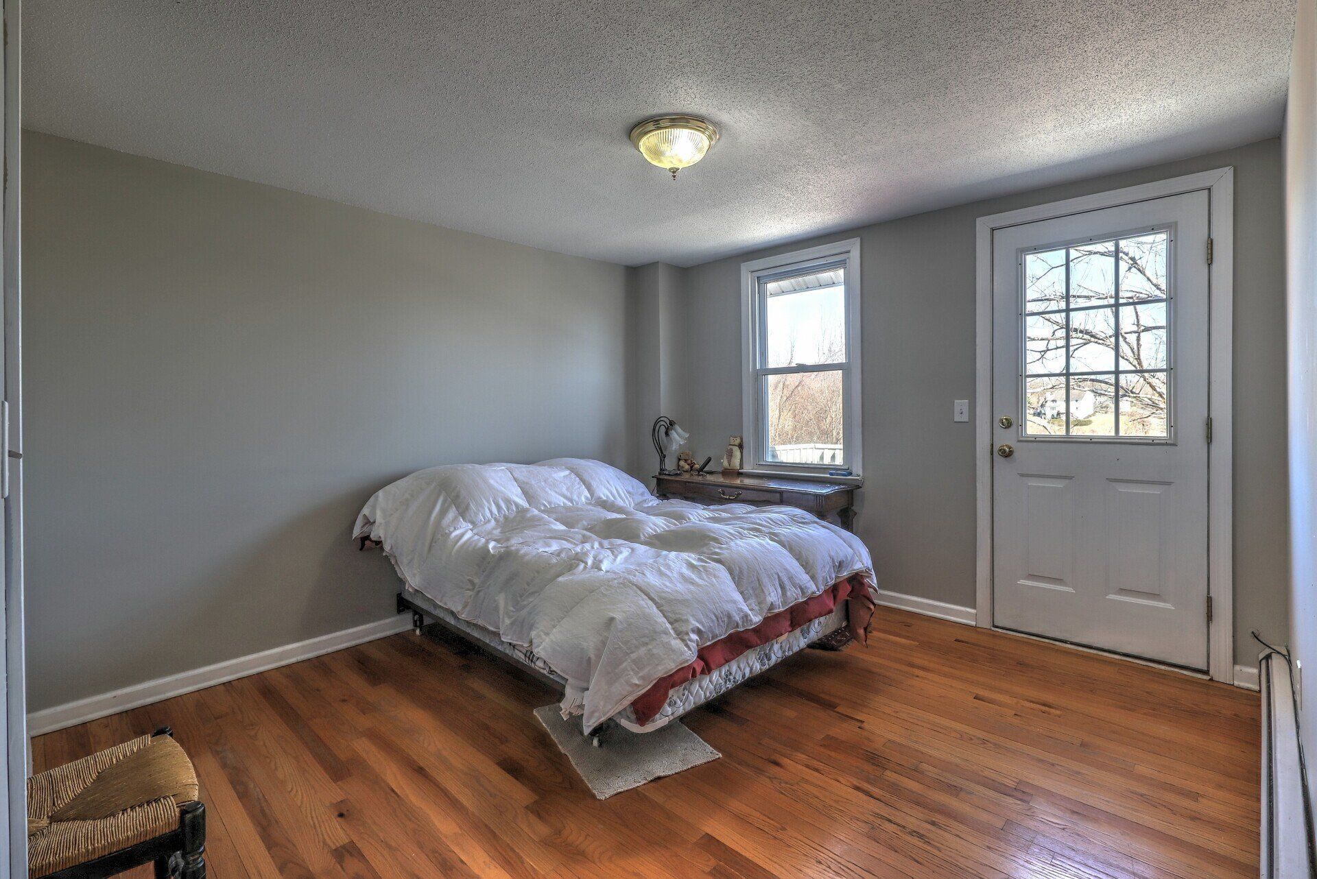 Bedroom with a bed, wood floor, gray walls, a window, and a door.