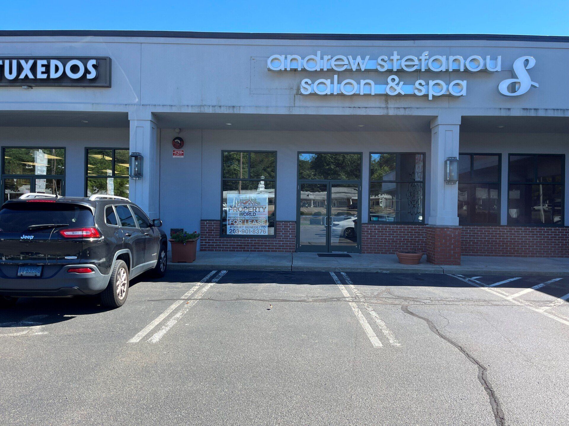 Andrew Stefanou Salon & Spa storefront with a black SUV parked in front on a sunny day.