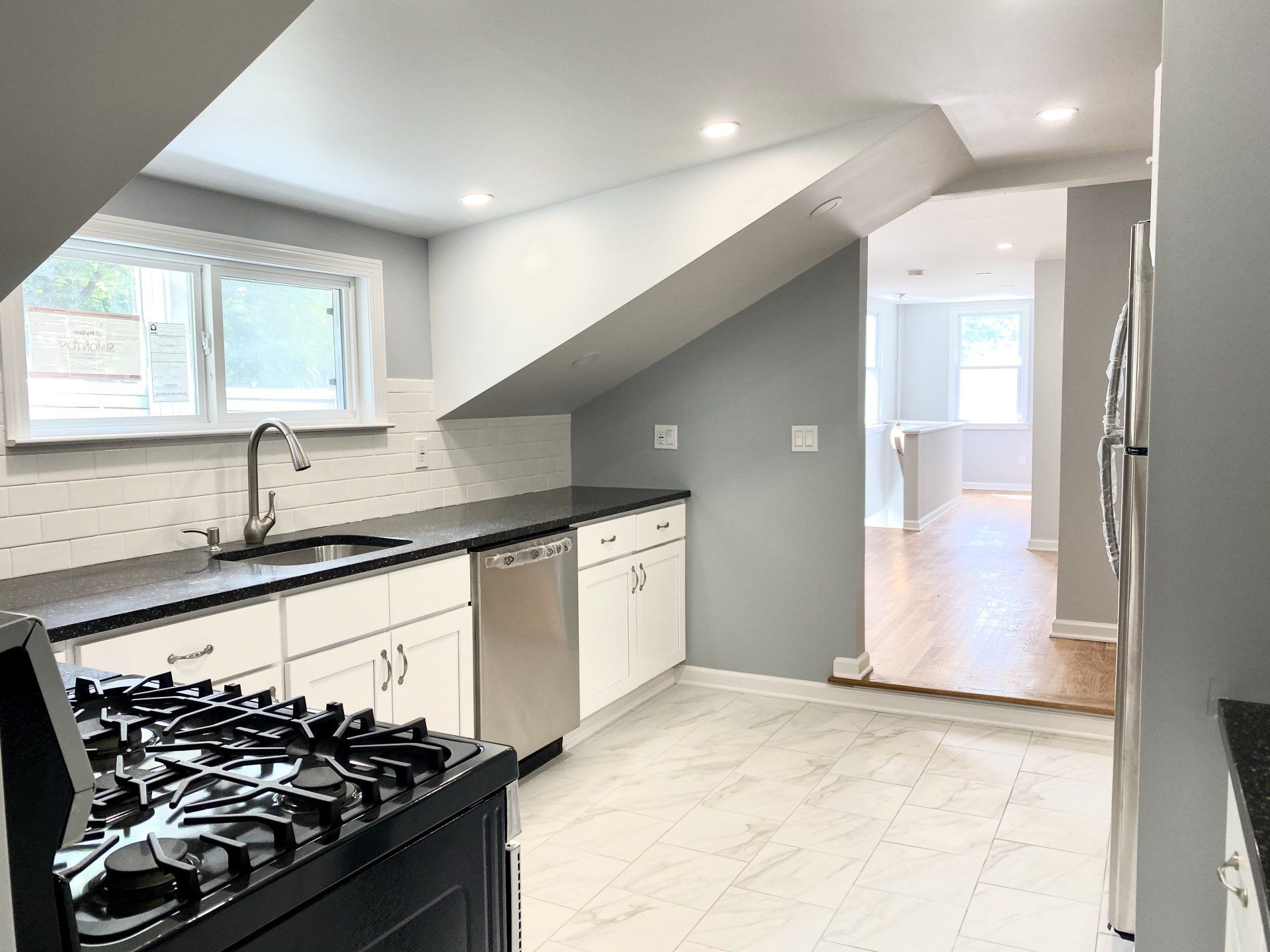 Modern kitchen with white cabinets, dark countertops, and stainless steel appliances.