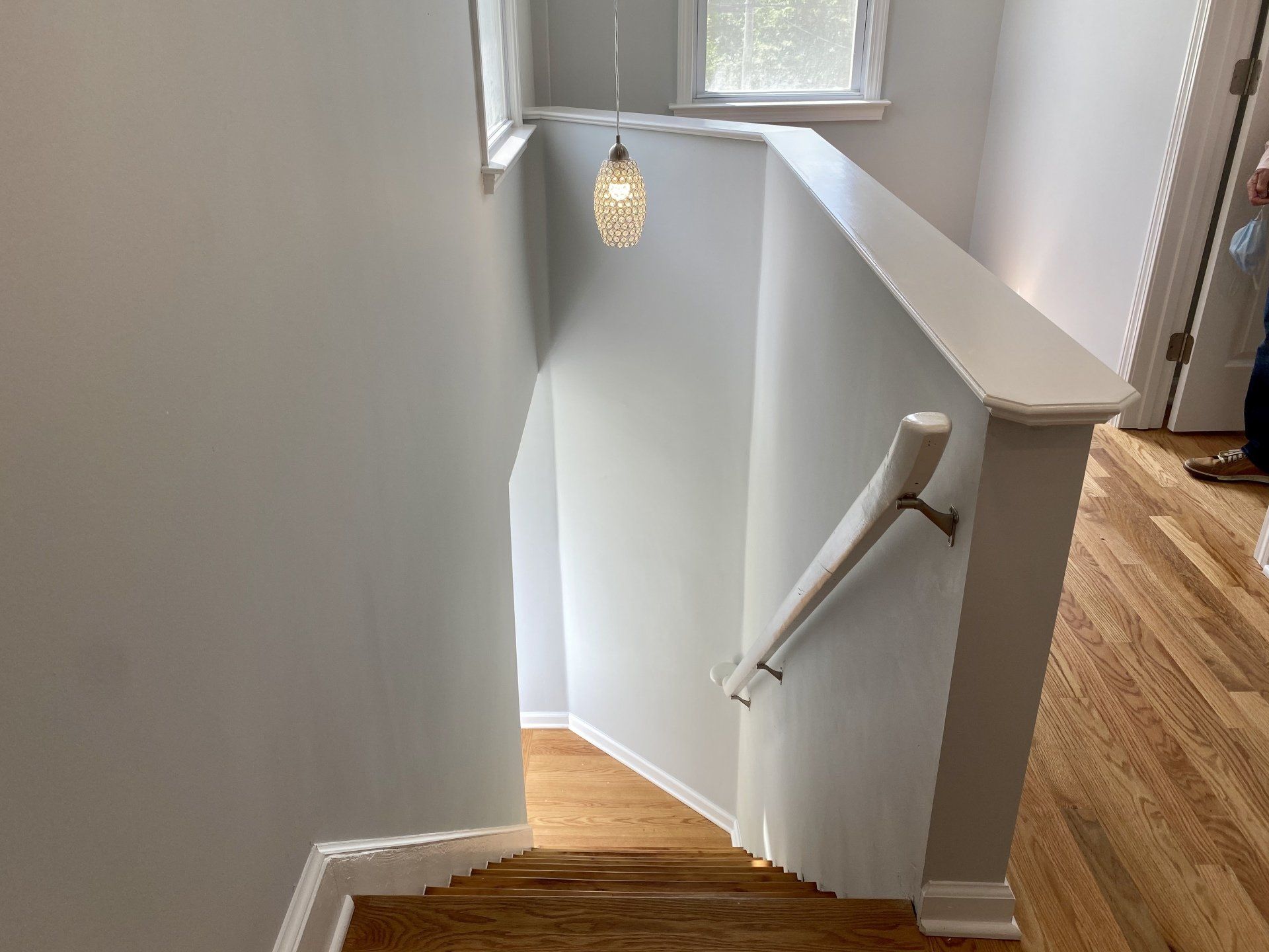 Staircase with light fixture overhead and hardwood floors, viewed from above.