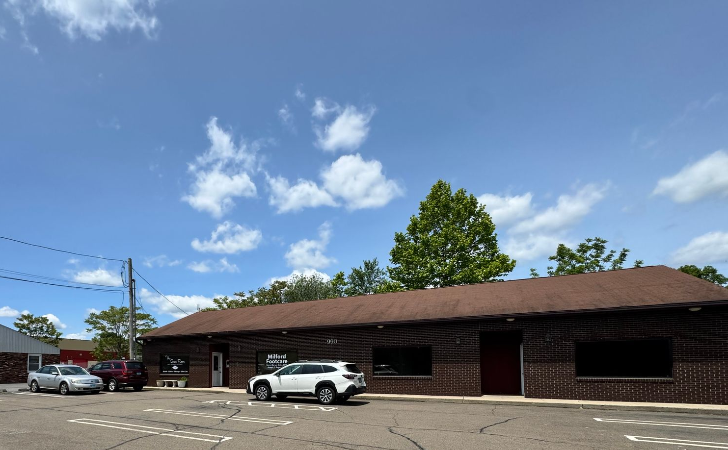 Parking lot with cars in front of a low brick building under a partly cloudy sky.