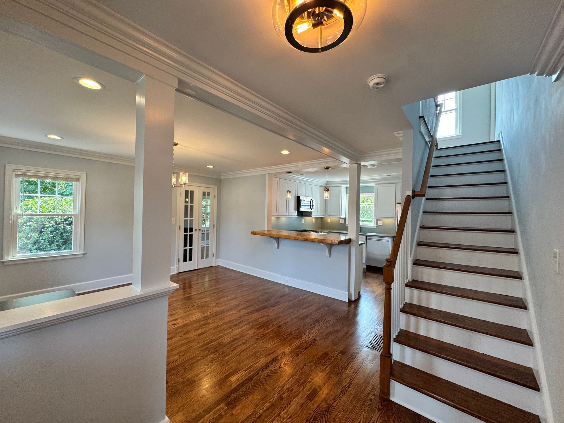 Interior view of a house with stairs, hardwood floors, and a light blue wall.