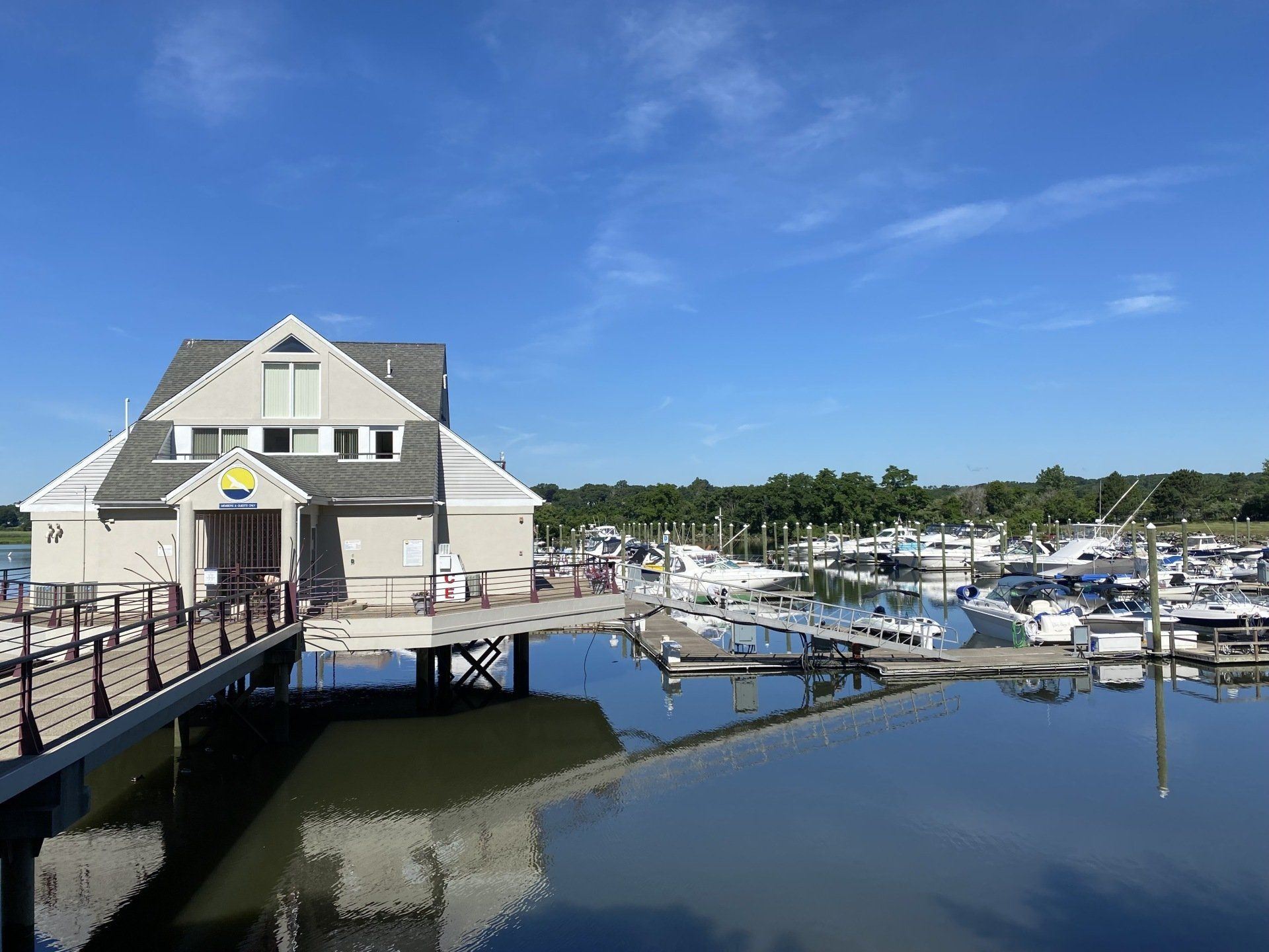 Boathouse over water with docked boats, under a bright blue sky.