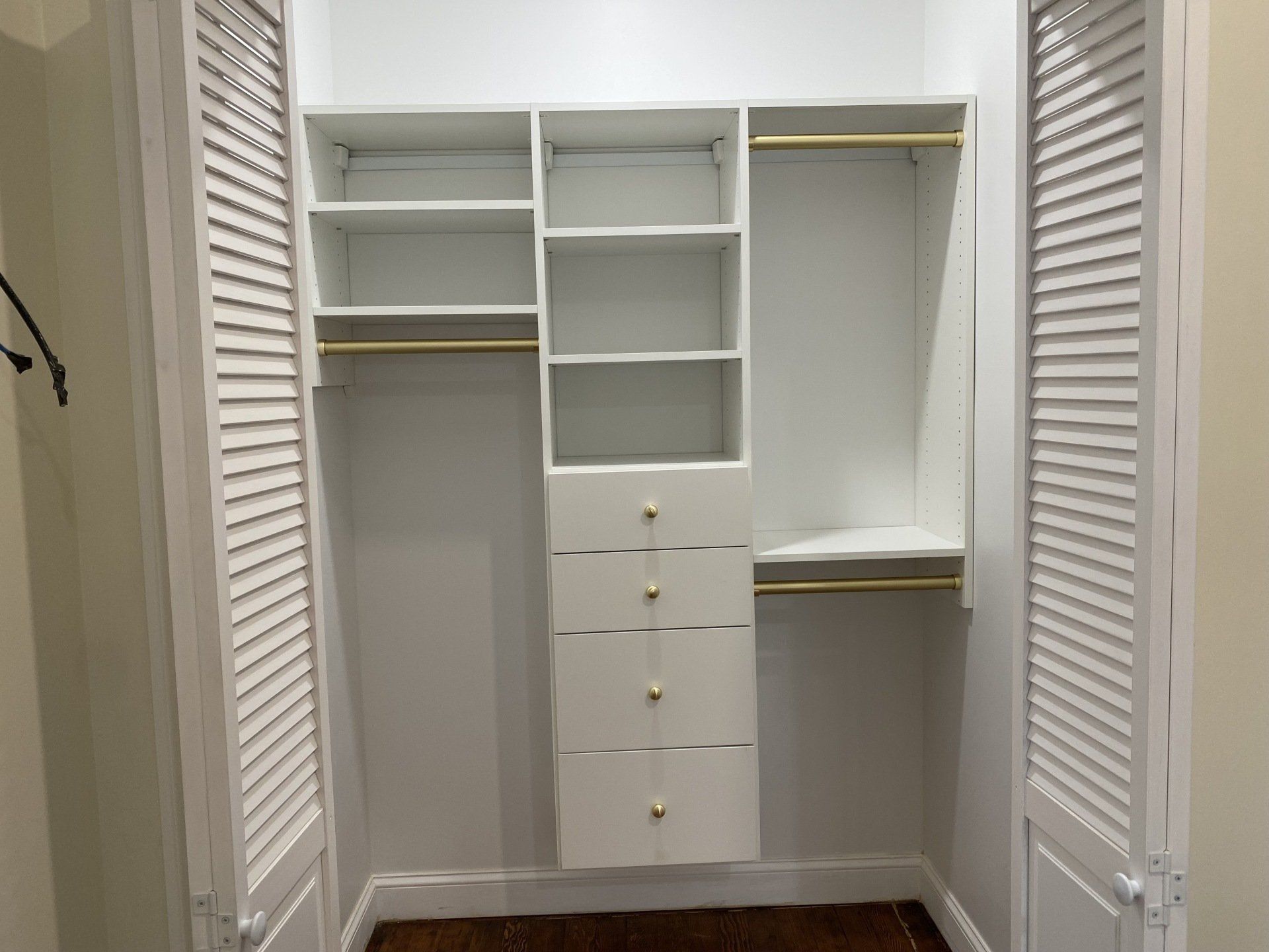 White closet with shelves, drawers, and hanging rods. Doors open.