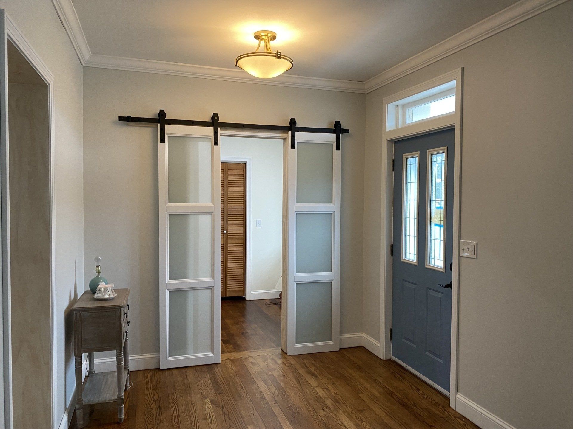 Hallway with wooden floor, frosted glass sliding doors, and a blue front door.