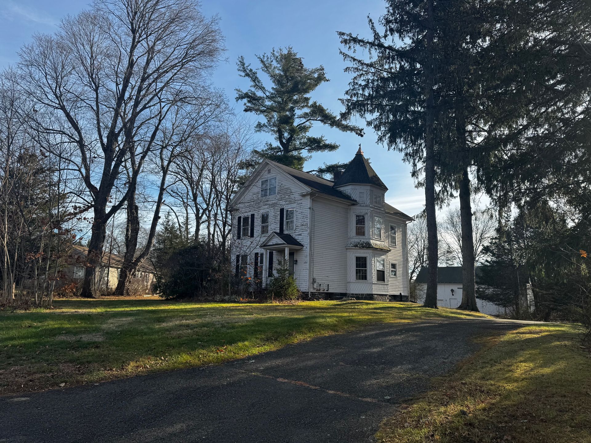 Three-story gray house under construction with multiple windows and a blue sky in the background.