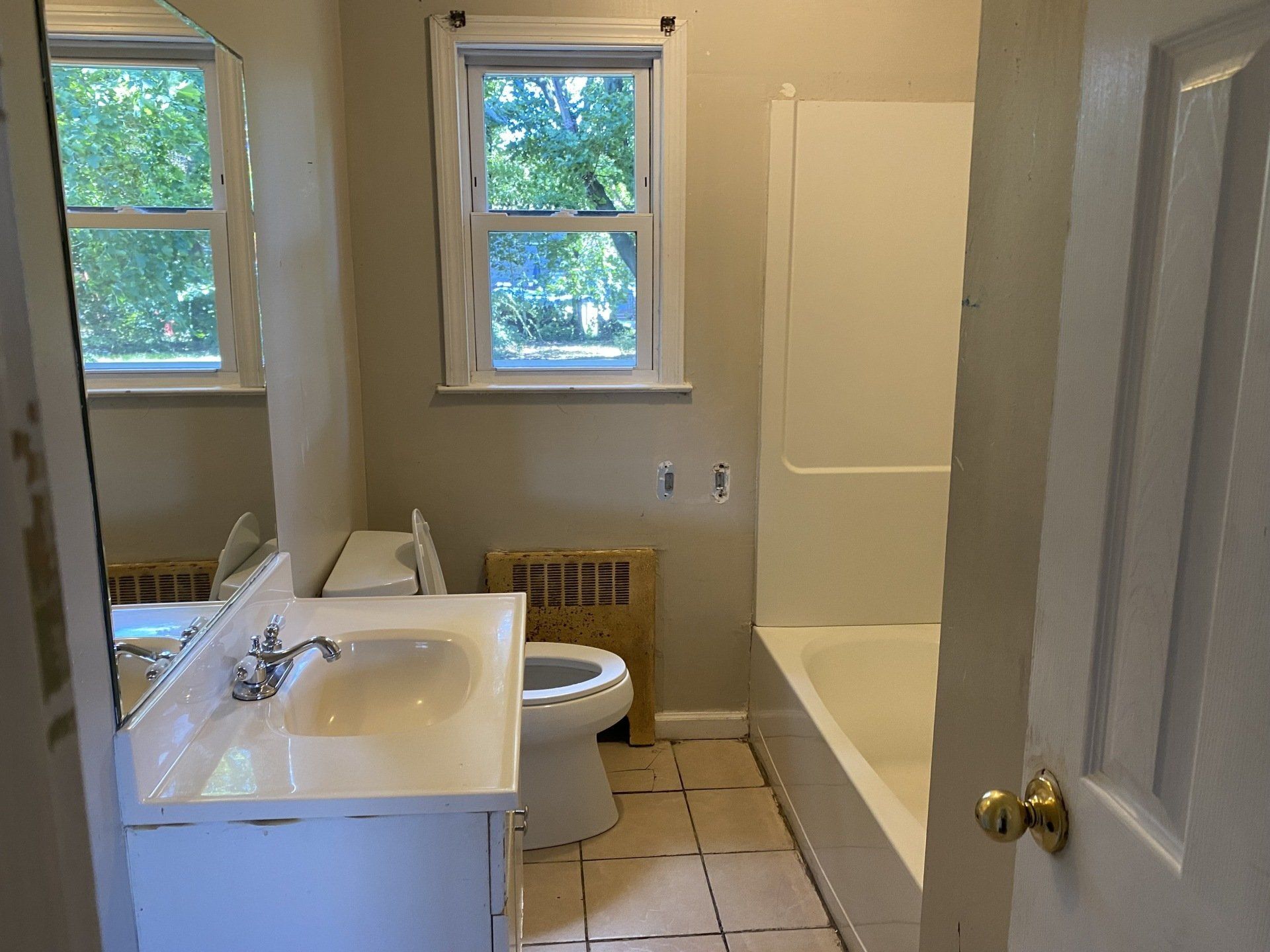 Bathroom with a sink, toilet, tub, window, and a radiator.