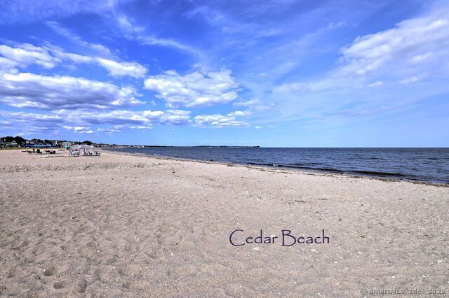Sandy Cedar Beach under a bright blue sky with white clouds; ocean to the right.