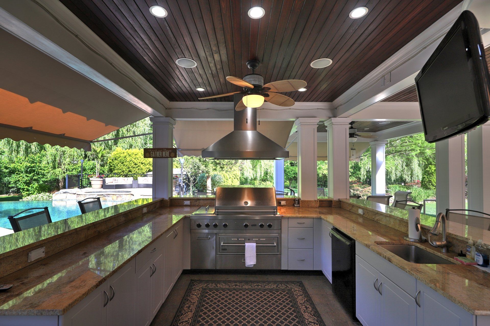 Outdoor kitchen with granite countertops, stainless steel appliances, and a wood ceiling.