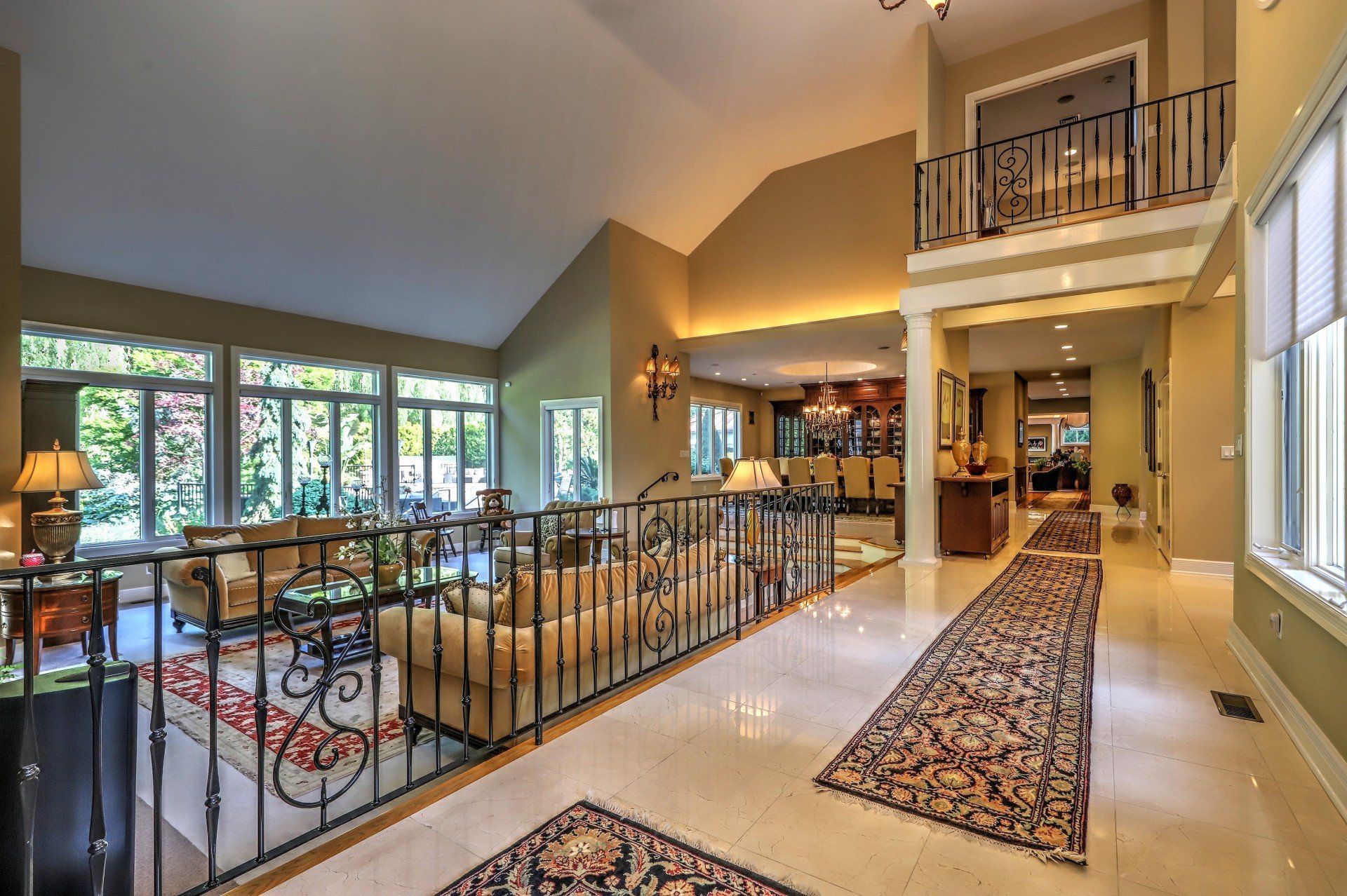 Elegant home interior with a balcony, large windows, and a long hallway with a patterned rug.