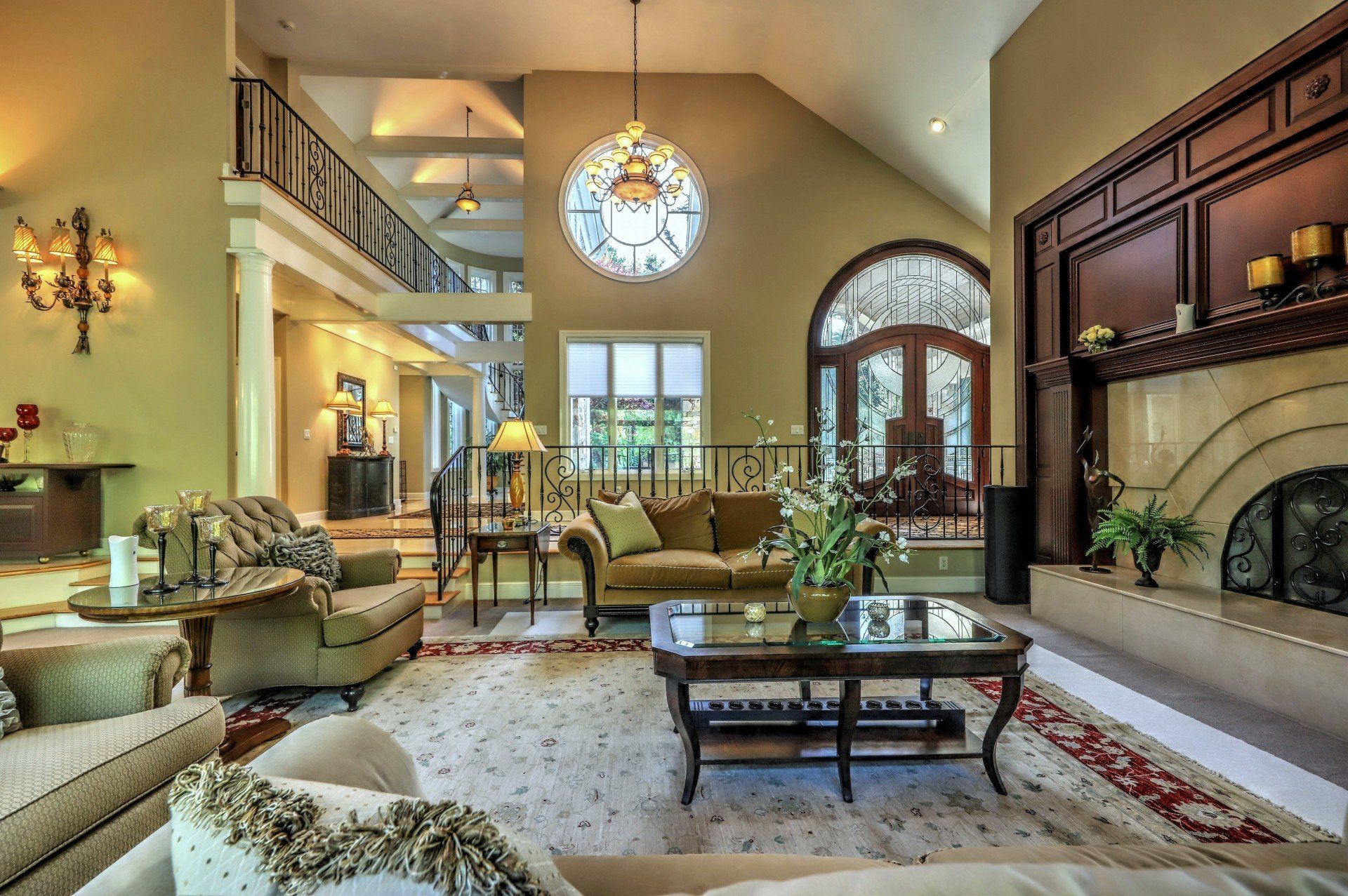Luxurious living room: cream sofas, fireplace, arched doorway, large circular window, balcony, beige walls.