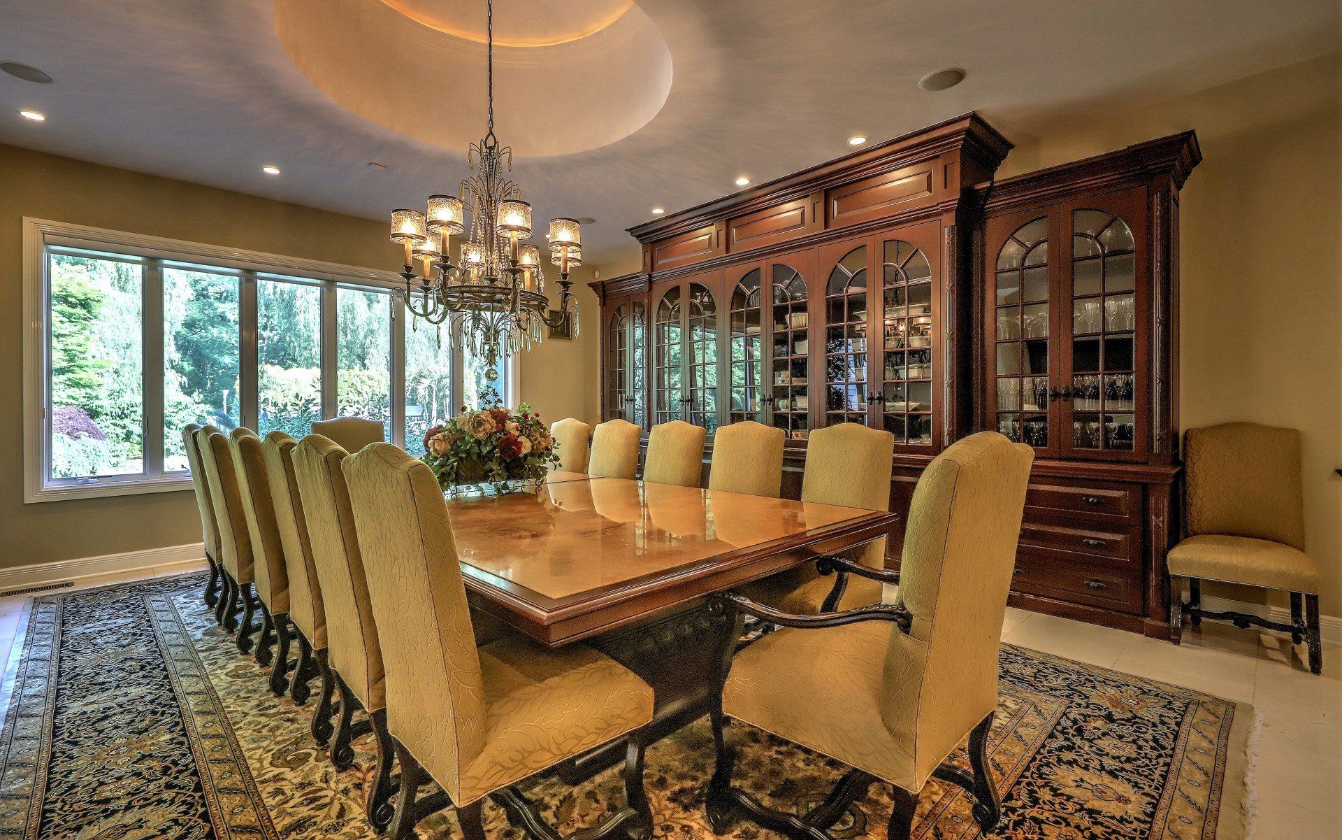 Elegant dining room with large table, chairs, and ornate wooden cabinet.
