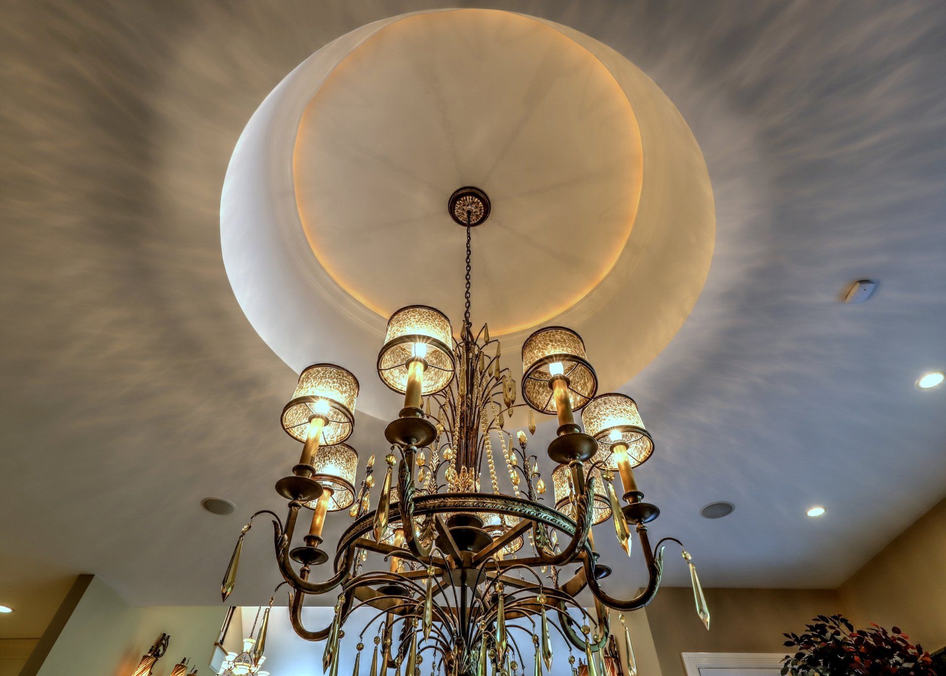 Chandelier hanging from a white dome ceiling with a golden inner ring.
