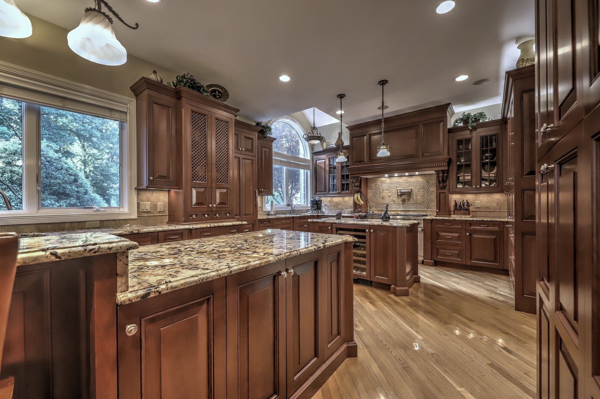 Elegant kitchen with wooden cabinets, granite countertops, and a large window overlooking trees.
