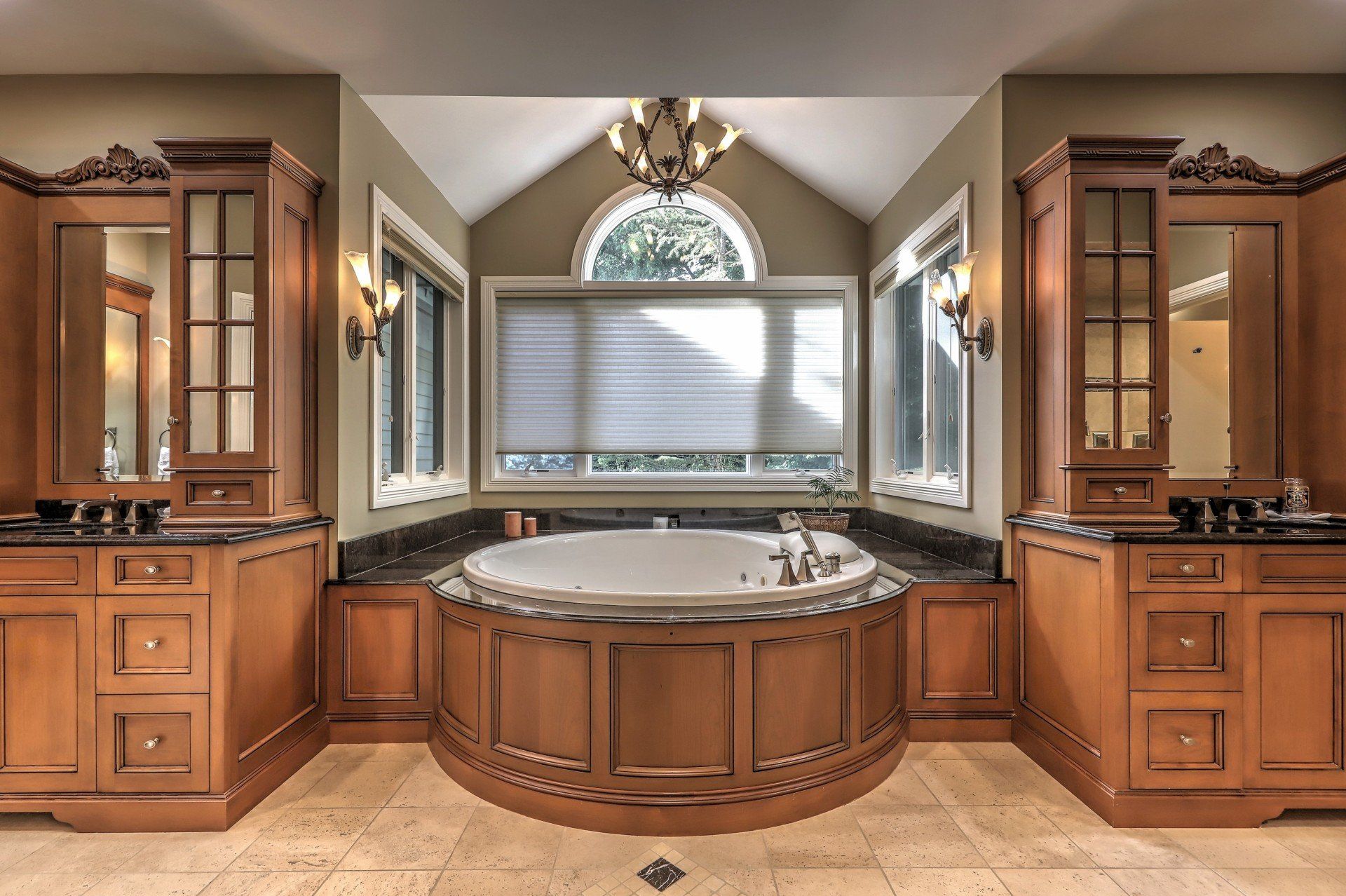 A luxurious bathroom with a circular tub, wooden cabinets, and large windows.