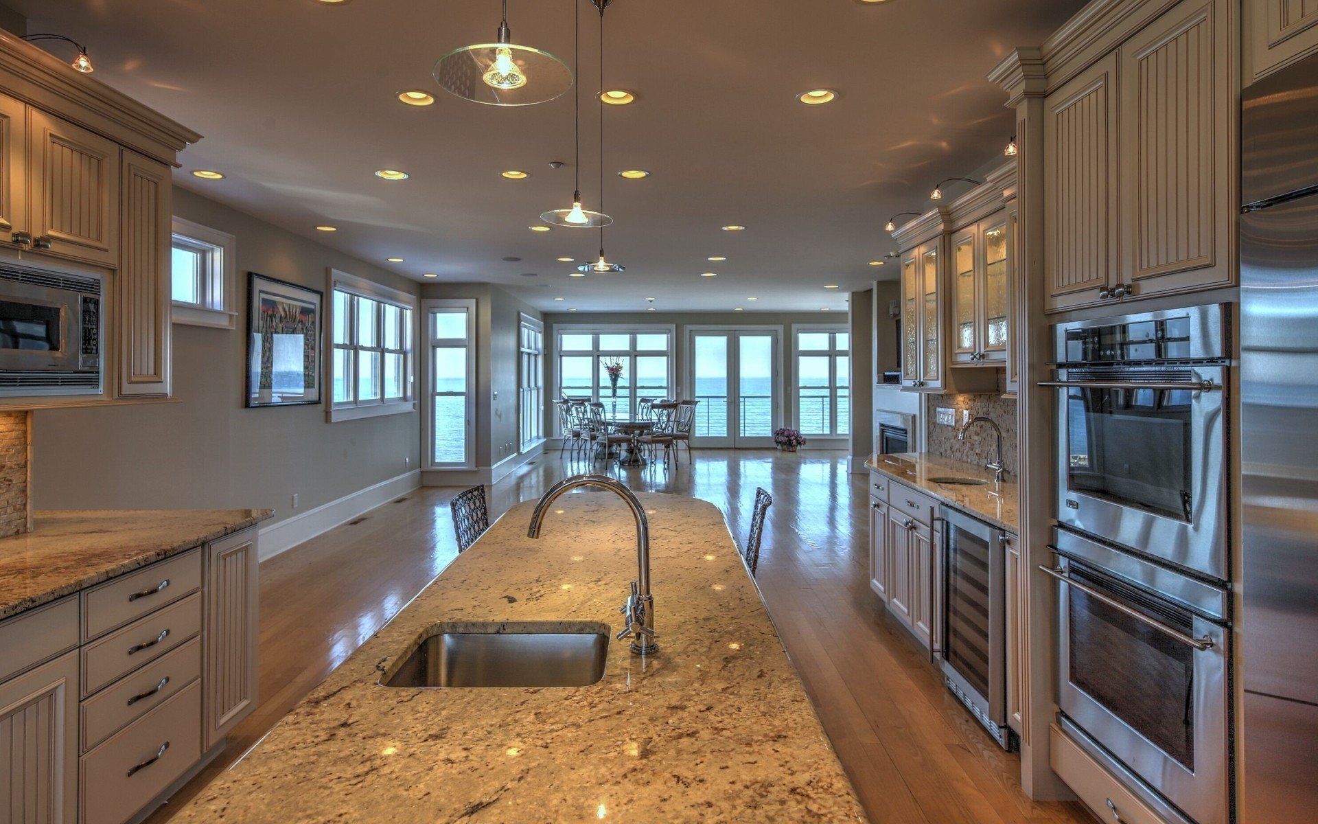 Spacious kitchen with granite counters, stainless steel appliances, and a view of the ocean through large windows.