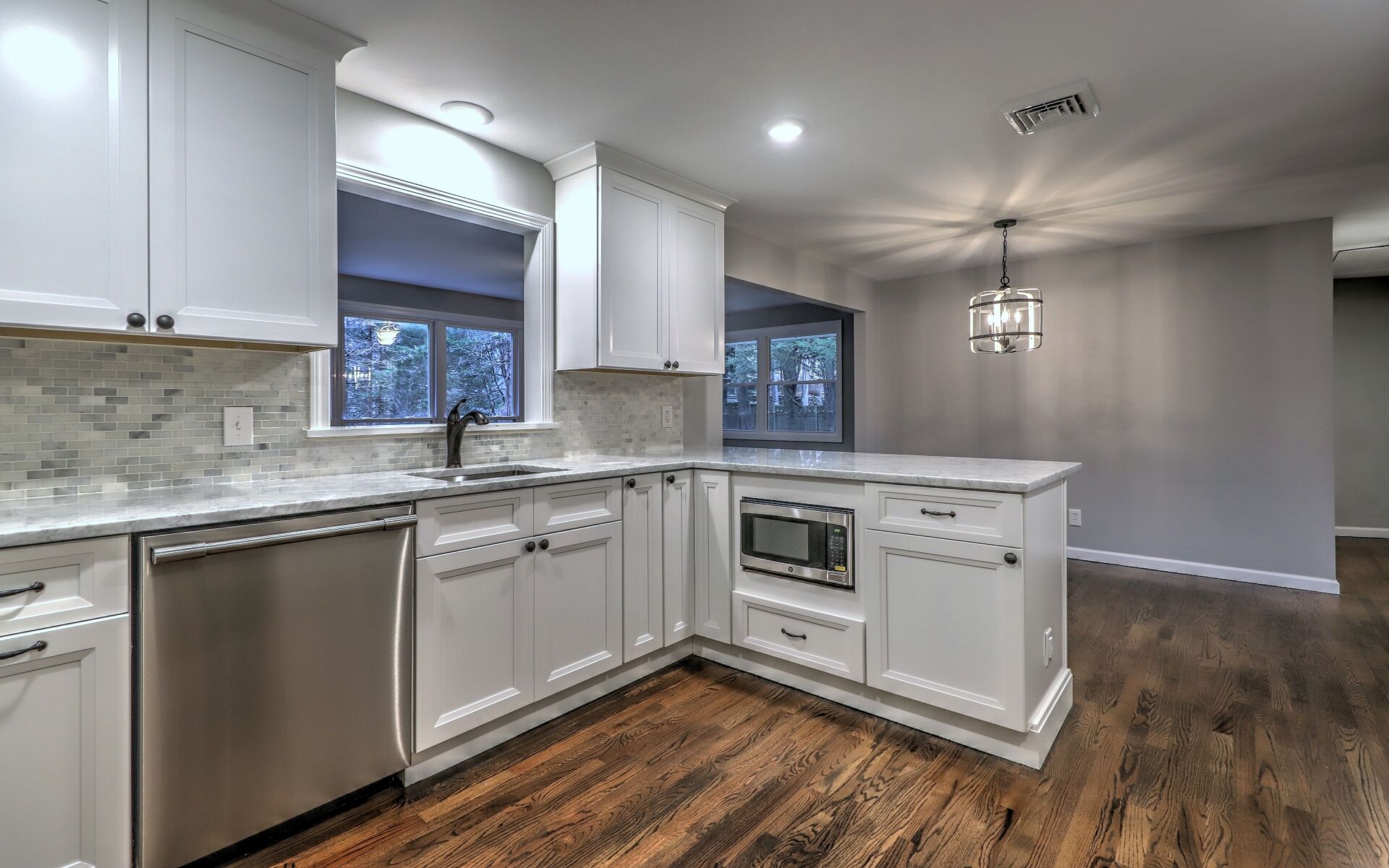 White kitchen with island, stainless steel appliances, and wood floors.