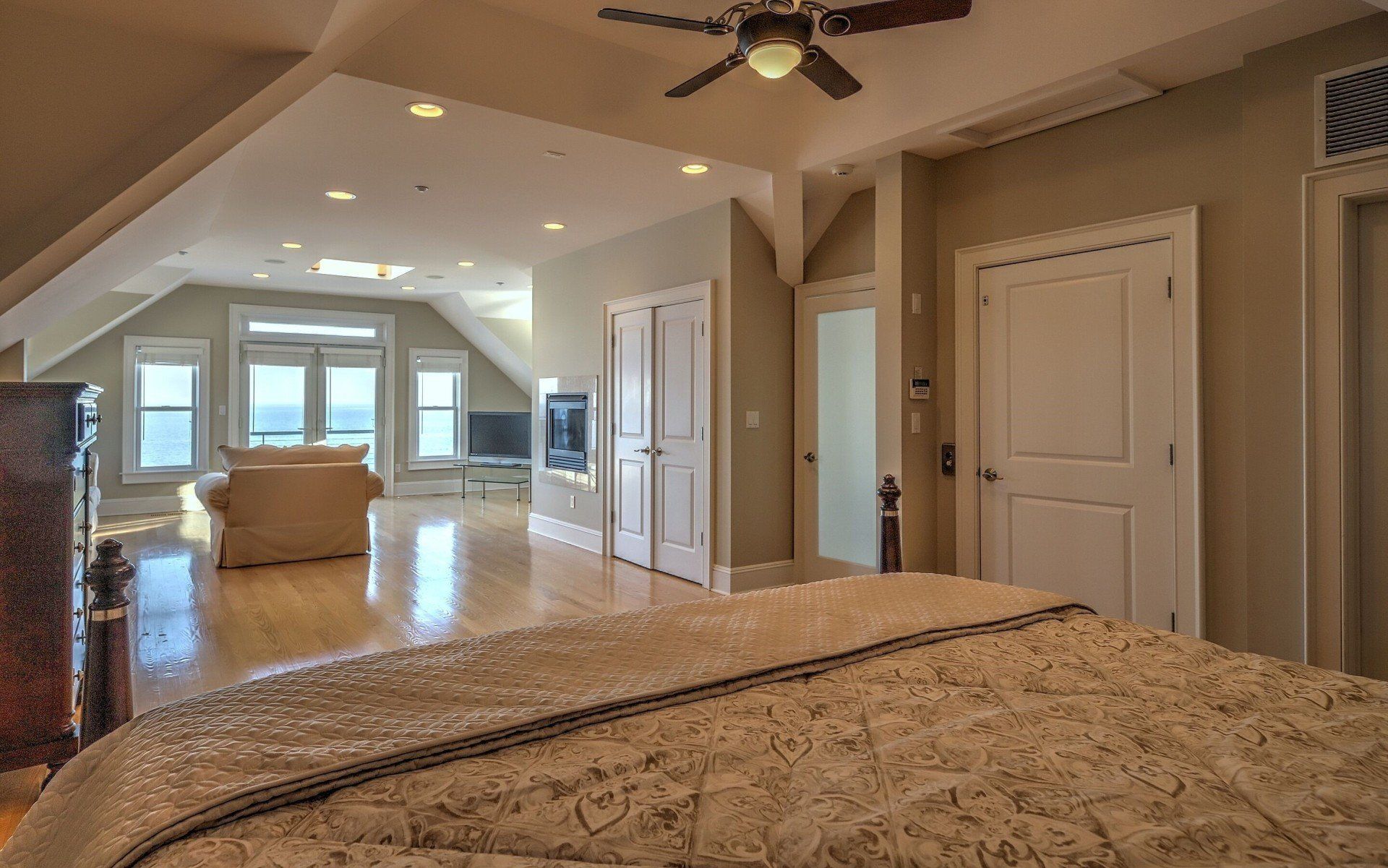 Spacious bedroom with a bed, windows overlooking the ocean, and a sitting area.