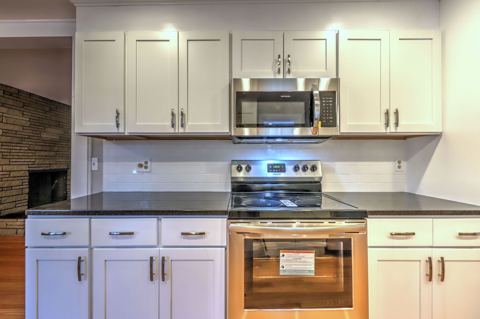 Light gray kitchen cabinets with a stainless steel range and microwave.