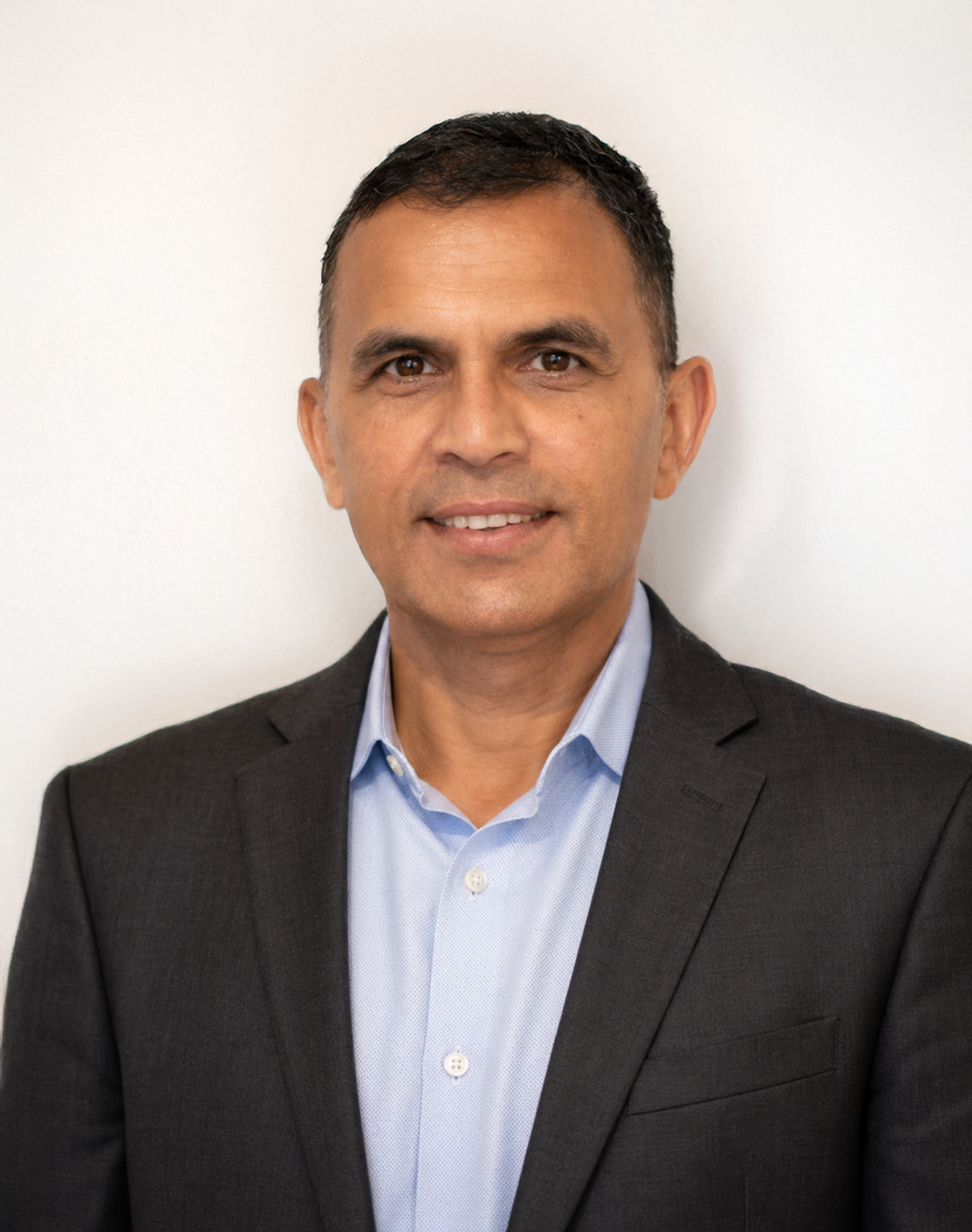 Portrait of a man in a dark blazer and light blue shirt against a white background