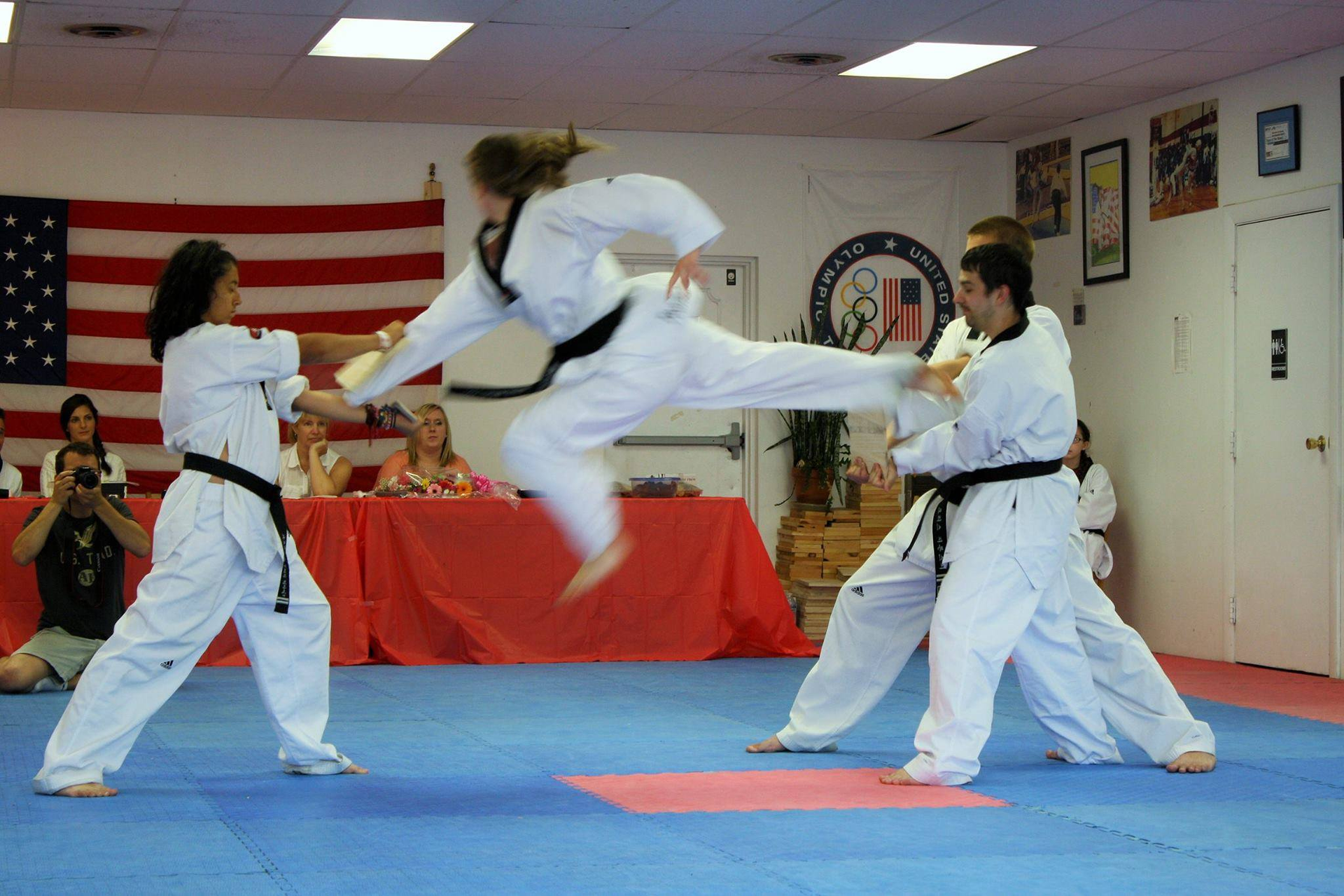 A group of people are practicing martial arts in front of an American flag. Mancino Academy Martial Arts
