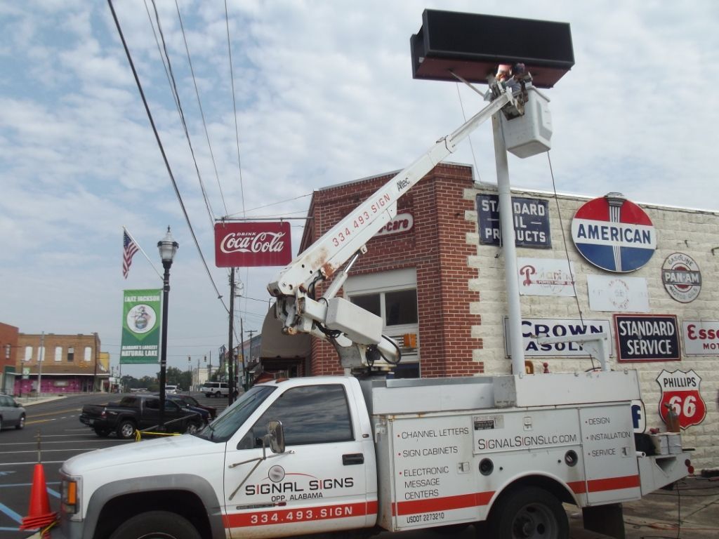 A white truck is parked in front of a coca cola sign