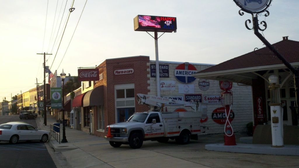 A white truck is parked in front of a pepsi sign