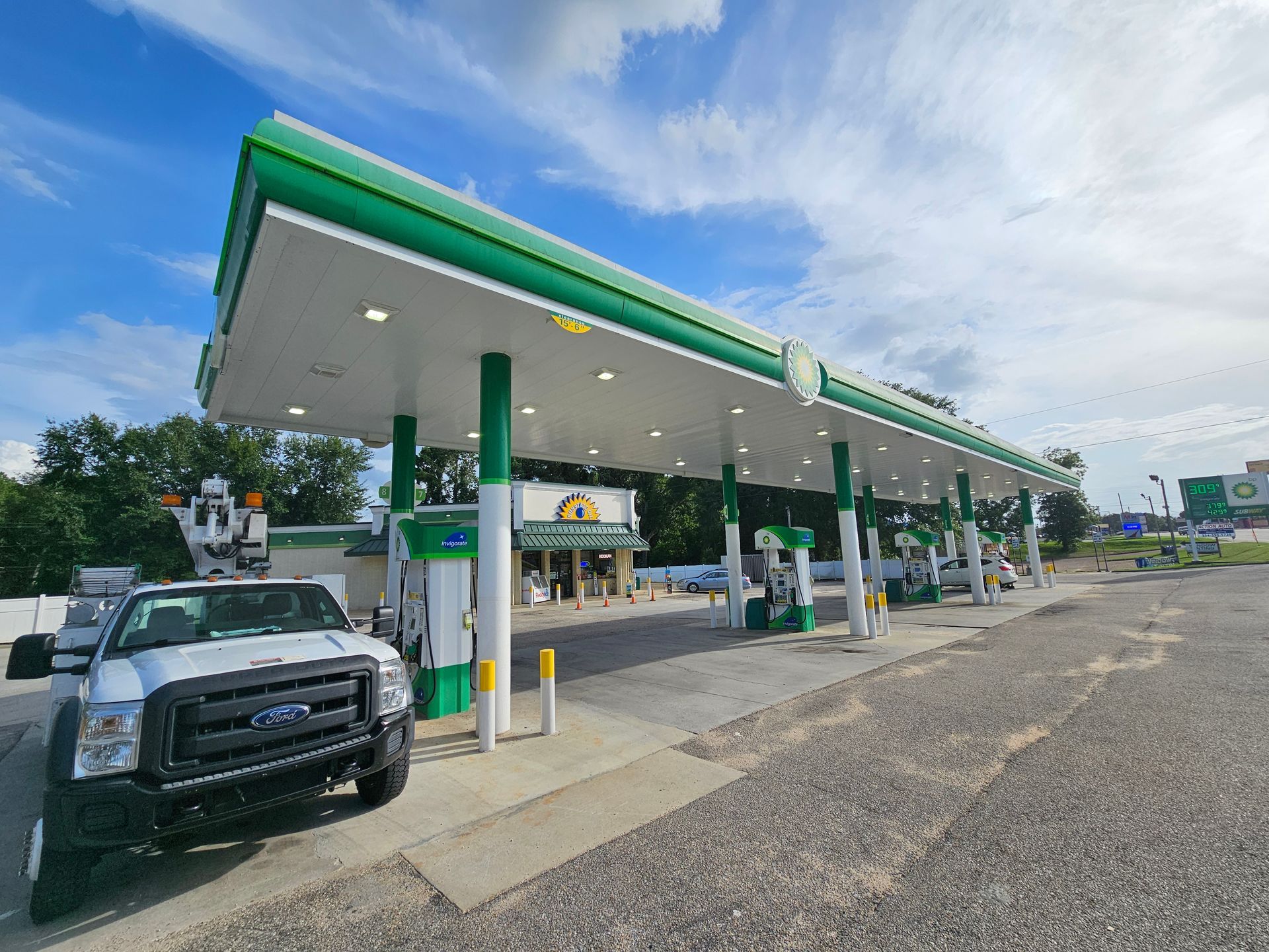 A white truck is parked in front of a gas station.