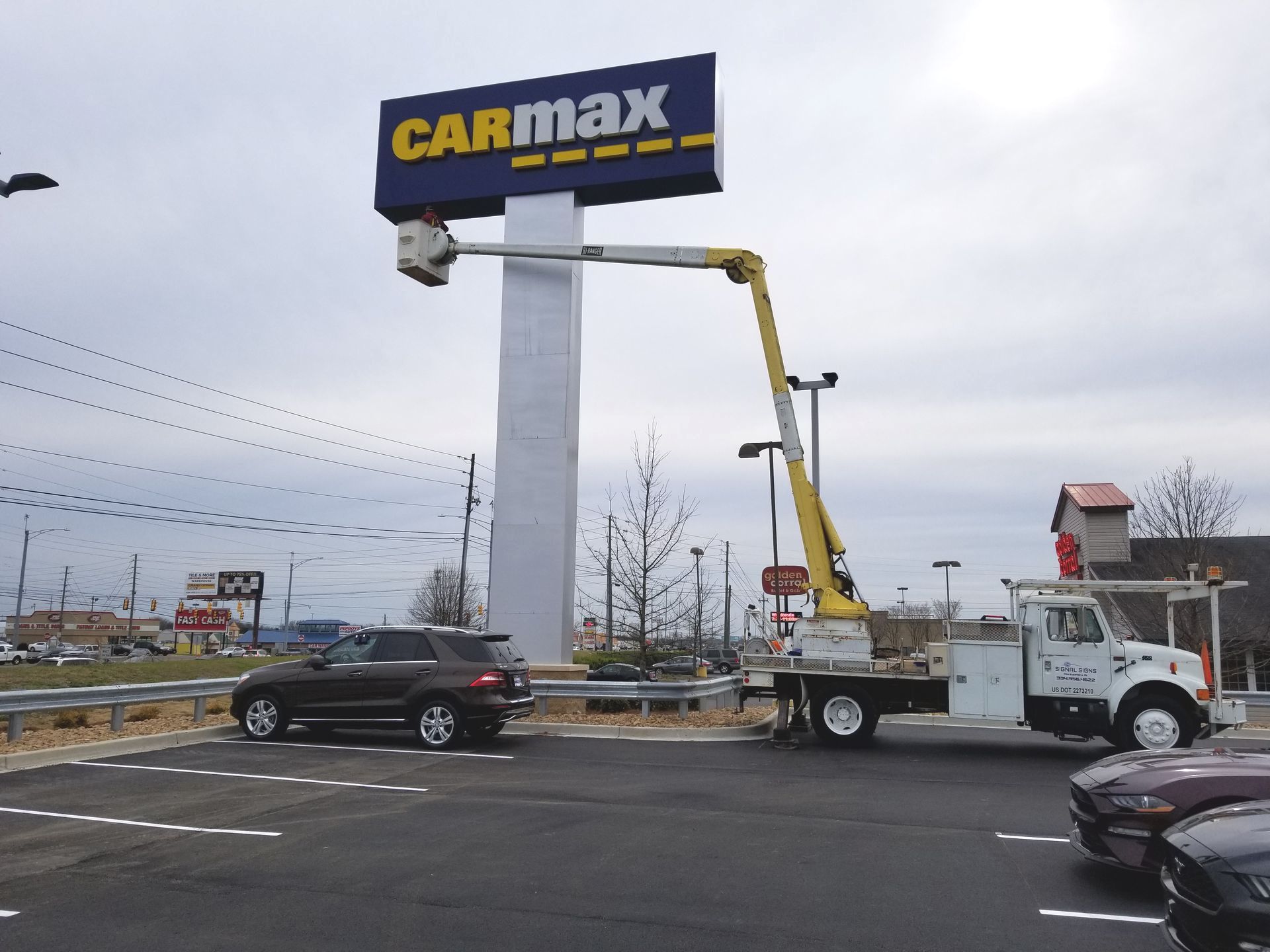 A carmax sign is being installed in a parking lot