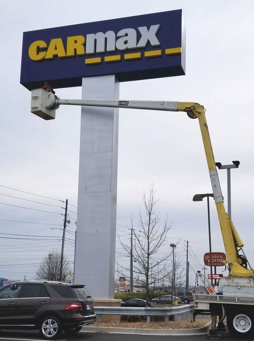 A carmax sign is being installed in a parking lot by Signal Signs, LLC.