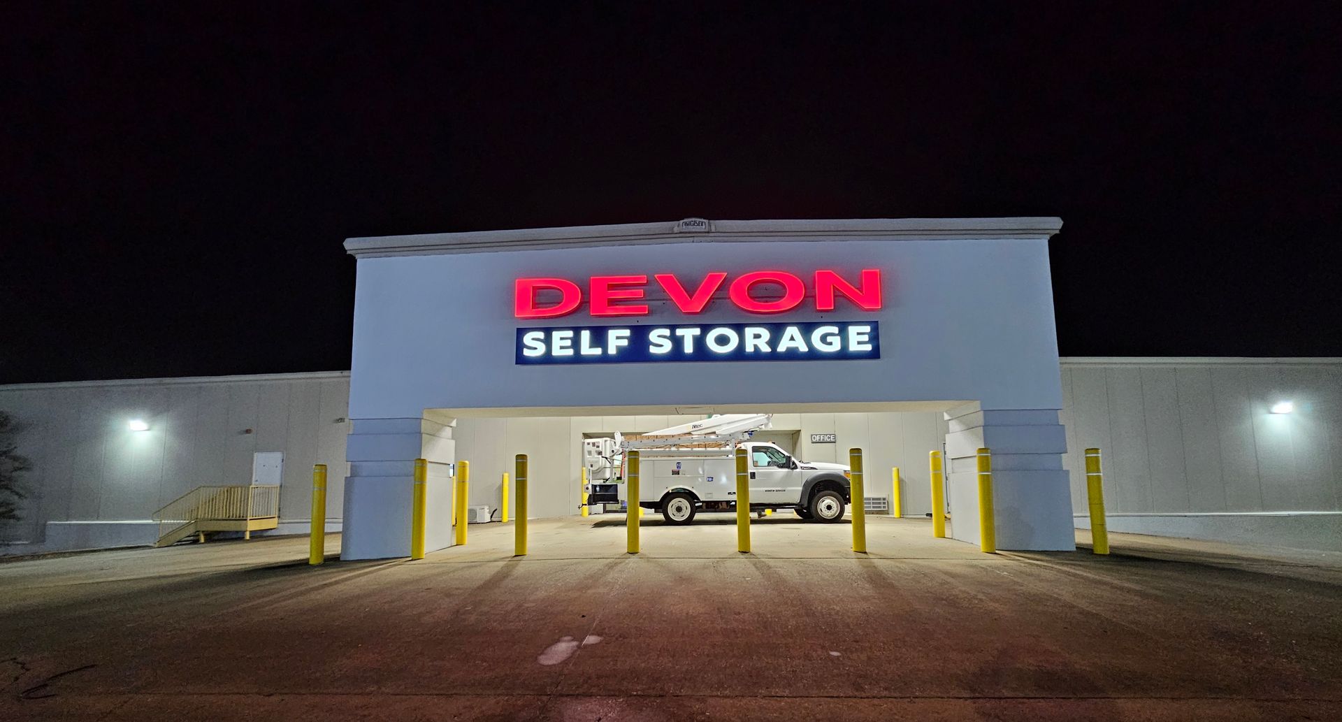 A white building with a red sign that says devon self storage