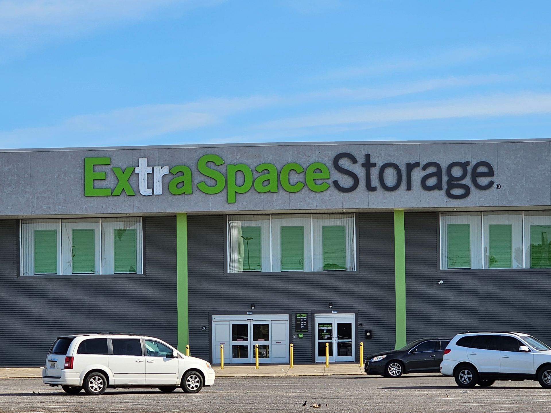 Two cars are parked in front of a building that says extra space storage.