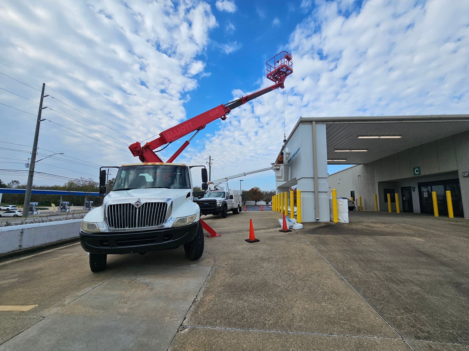 A white truck with a red crane on the back is parked in front of a building.