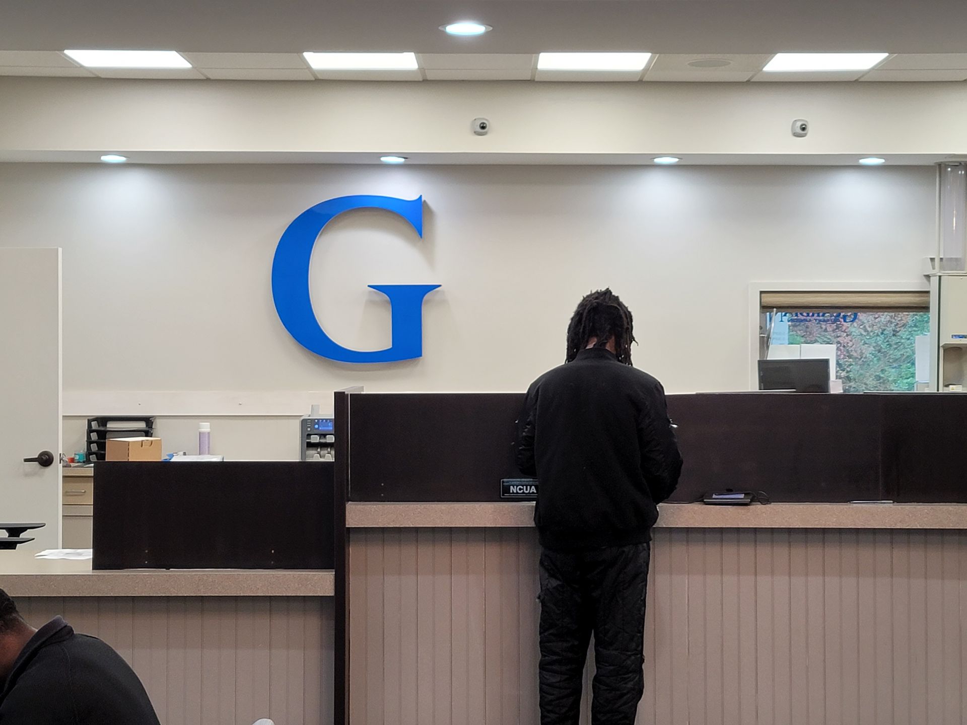 A man is standing at a counter in front of a large blue letter g