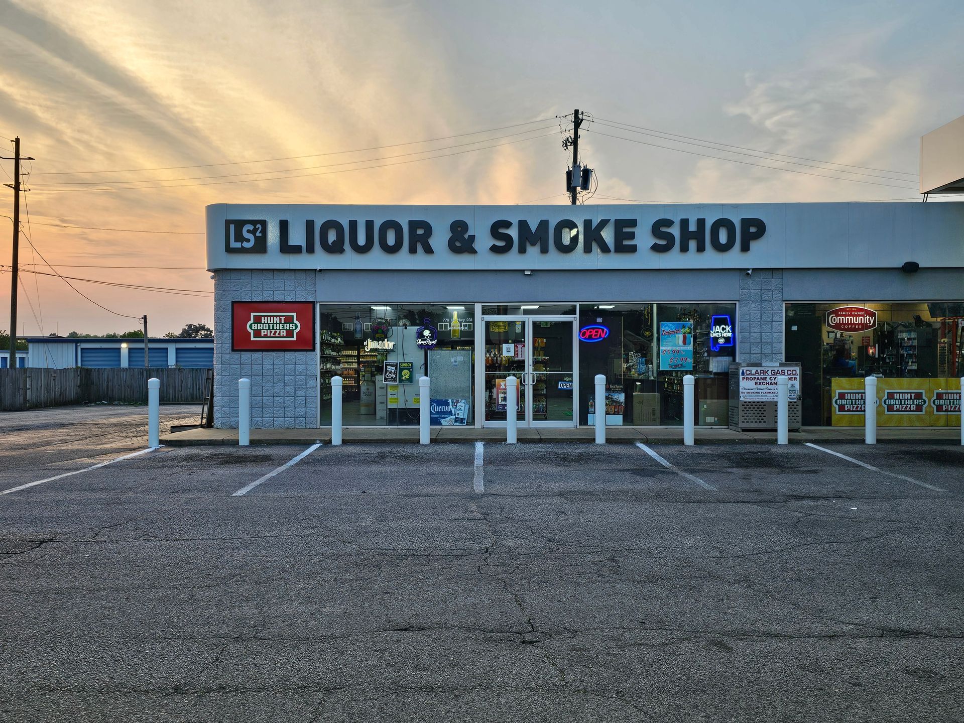 A liquor and smoke shop with a parking lot in front of it.